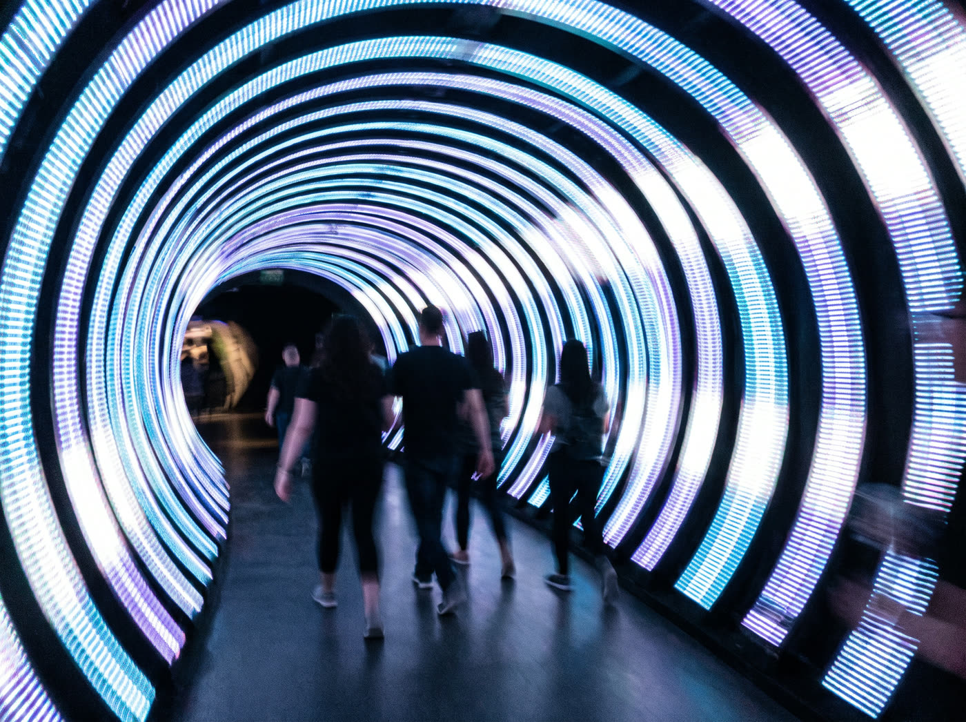 An immersive LED tunnel installation with silhouetted visitors walking through